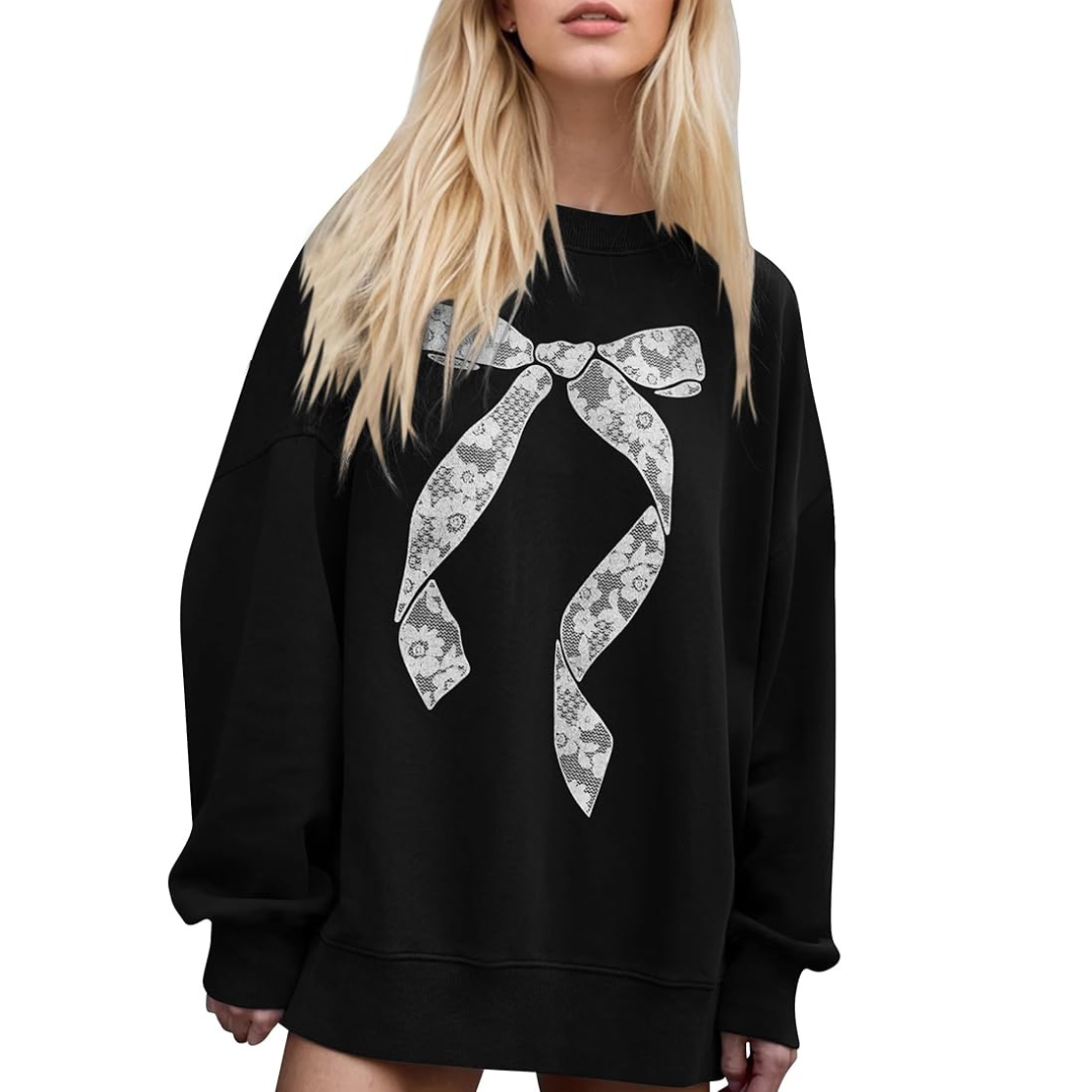 A woman wearing a black sweatshirt with a white lace print bow.