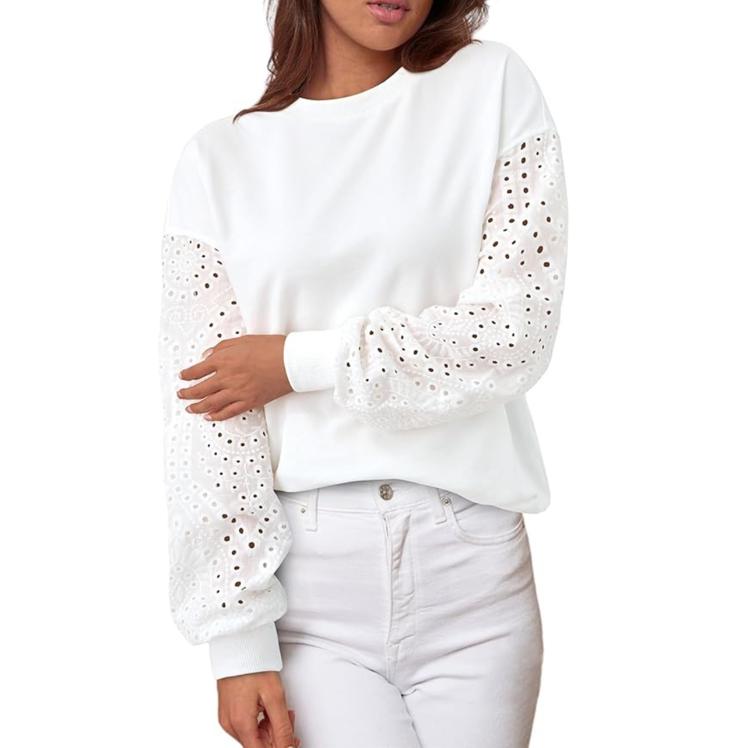 A woman wearing a white sweatshirt with eyelet sleeves.